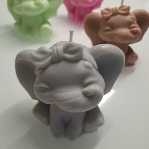 Handgemachte hellgraue Elefanten Kerze aus Sojawachs in sitzender Position auf dekorativem Untergrund.